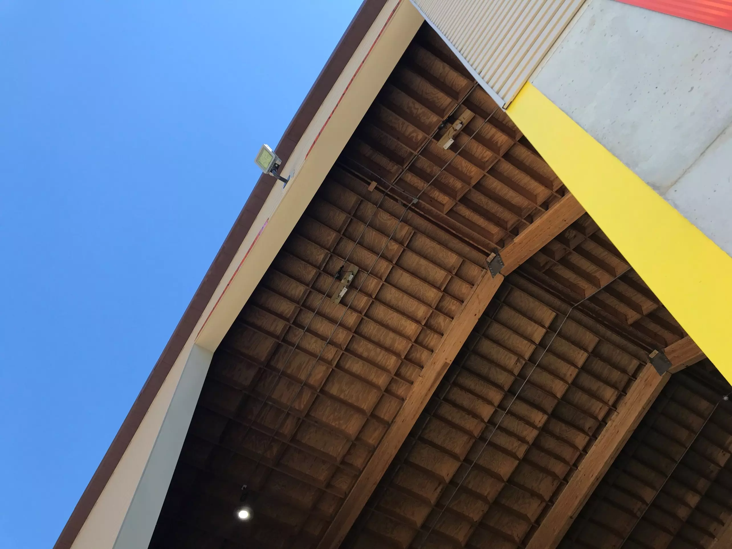 An image showing the interior of the wooden roof of a rock salt stockpile shed, with a view of the blue sky above the building.